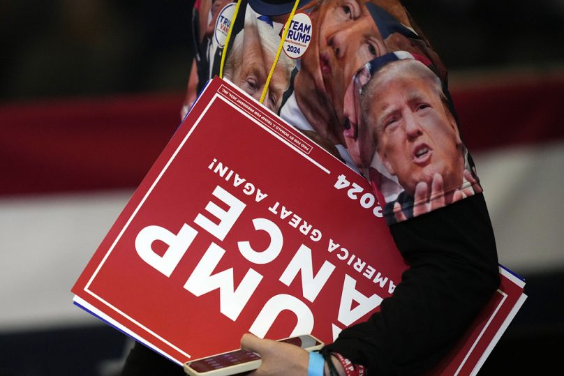 Un partisan porte des pancartes après un rassemblement électoral de Trump en Caroline du Nord.