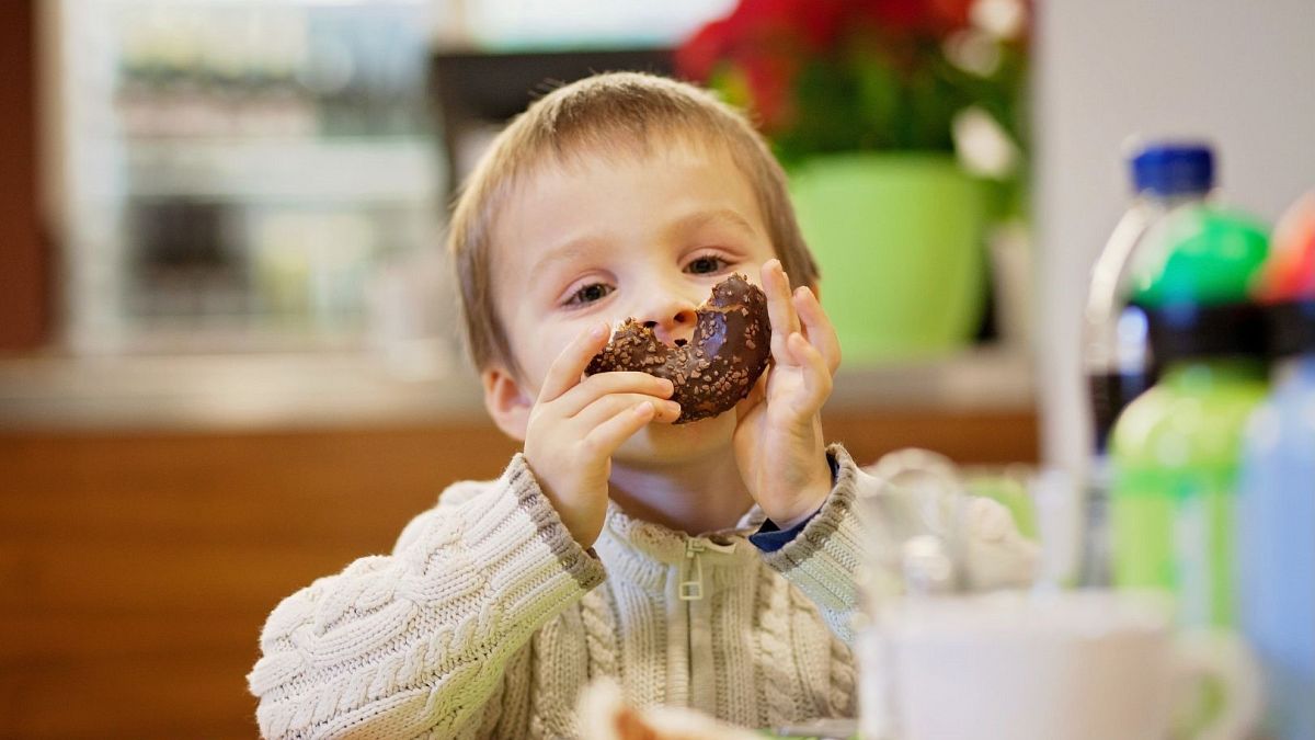 A child holds up a doughnut.