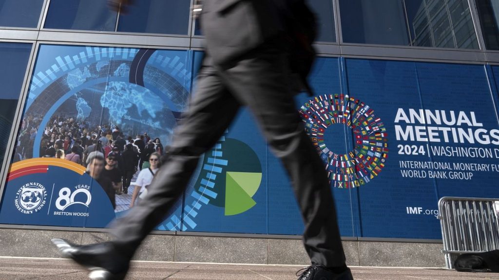 A delegate walks by an IMF banner, during the World Bank/IMF Annual Meetings at the International Monetary Fund (IMF) headquarters in Washington