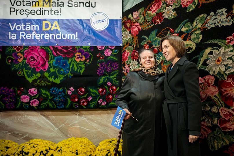 La présidente moldave Maia Sandu, à droite, pose avec une femme tenant un drapeau sur lequel est écrit « Nous votons oui au référendum » lors d'une réunion électorale à Magdaceti, le 17 octobre 2024.