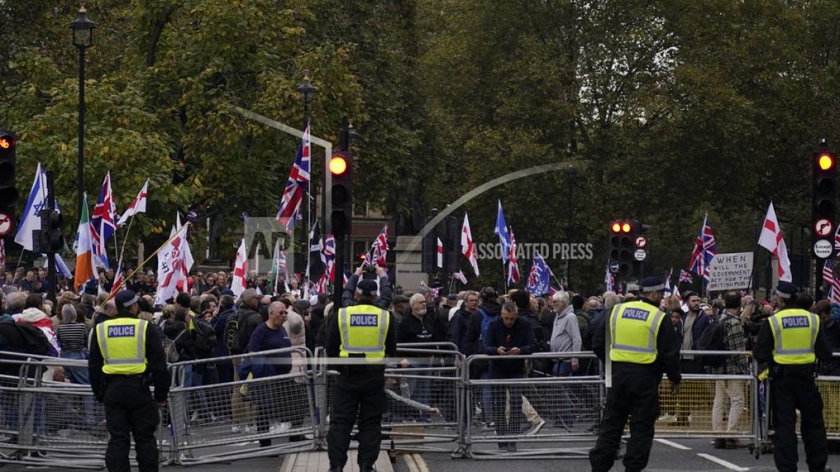 Far right pro-UK rally protesters endorsed by Tommy Robinson, demonstrate behind a police line in London, Saturday, Oct. 26, 2024.