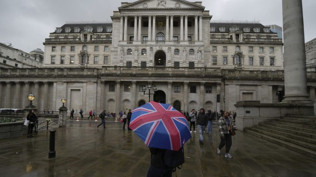 A woman with an umbrella stands in front of the Bank of England, at the financial district in London, , Nov. 3, 2022.