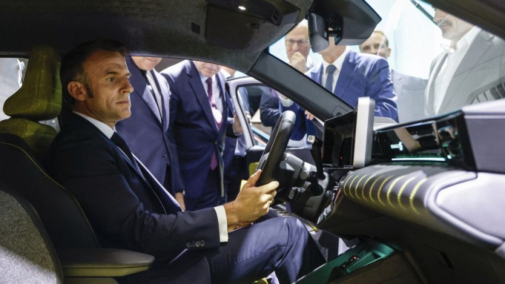 French President Emmanuel Macron sits in Renault R5 car as he visits the Renault stand at the Paris Auto Show in Paris, Monday, Oct. 14, 2024.