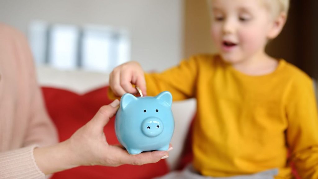 A child putting a coin into a piggy bank