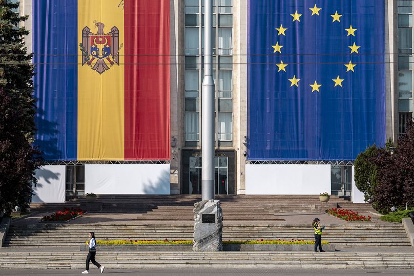 Une femme passe devant le bâtiment gouvernemental décoré de drapeaux de l'Union européenne et de la Moldavie à Chișinău, le 31 mai 2023.