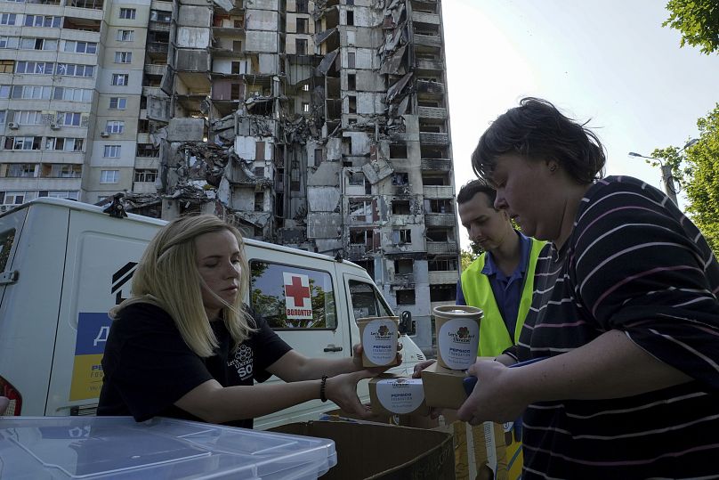 Les résidents locaux reçoivent des repas gratuits de la part de bénévoles dans le contexte de leur immeuble, endommagé lors de l'attaque à la roquette russe, à Kharkiv, en Ukraine, le 2 juin 2023.