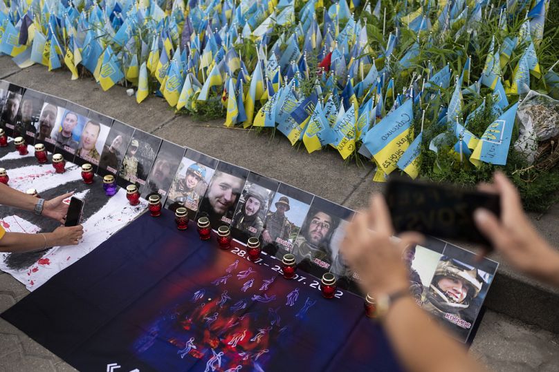 Des photos de prisonniers de guerre ukrainiens tués dans les explosions dans la caserne sous contrôle russe d'Olenivka sont placées autour d'un mémorial à Kiev, le 29 juillet 2023.