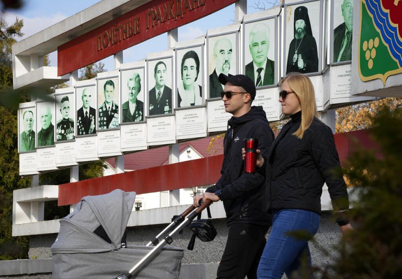 Un couple passe devant un panneau publicitaire avec des portraits de résidents honoraires de la ville de Tiraspol, le 31 octobre 2021