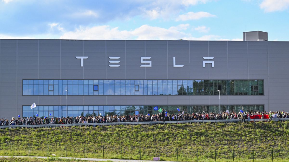 Demonstrators walk past the Tesla factory in Grunheide, Germany on Saturday, May 11, 2024, at the end of their protest.