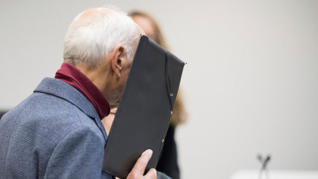 The defendant stands in front of the district court and covers his face before the verdict, in Berlin, Monday, Oct. 14, 2024.