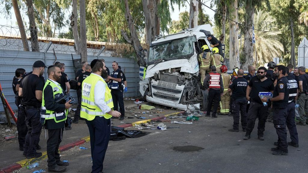 Israeli police and rescue workers climb on a truck to inspect the body of a driver that rammed into a bus stop near the headquarters of Israel