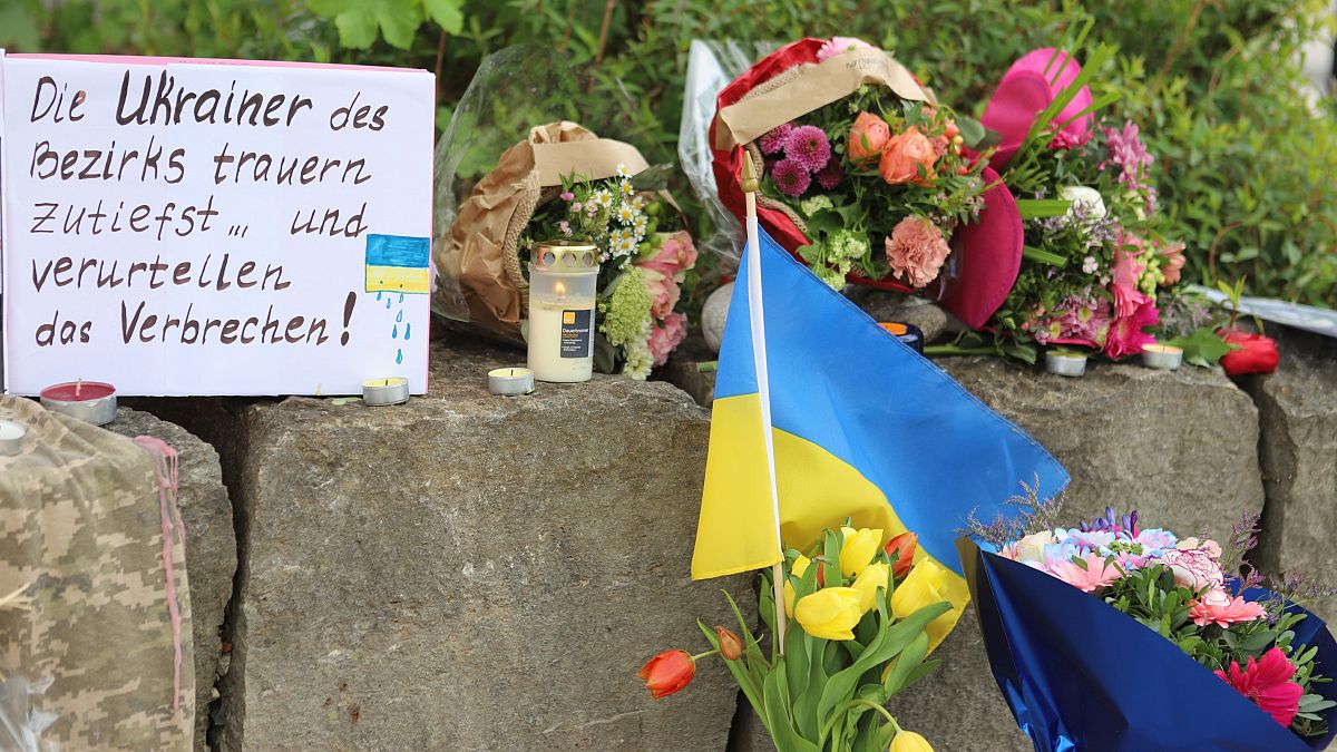 Flowers and a small Ukrainian flag are laid at a shopping center in Murnau, Germany after a stabbing.