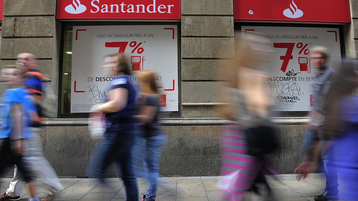 In this photo taken on Tuesday Oct. 22 2013, people walk past a Santander bank branch in Barcelona, Spain.