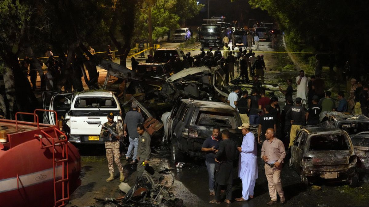 Security officials inspect the scene of an explosion near Karachi airport that resulted in injuries and damaged vehicles.