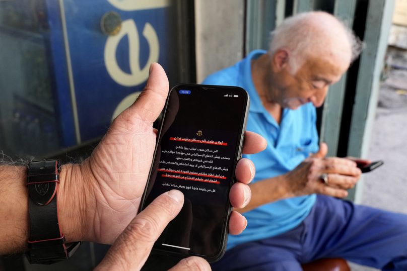 Des hommes lisent des alertes sur leurs téléphones portables indiquant aux habitants du sud du Liban de ne pas rentrer chez eux jusqu'à nouvel ordre.