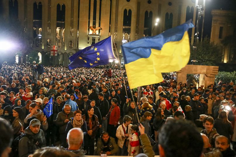 Des manifestants brandissent des drapeaux nationaux de l’UE et de l’Ukraine alors qu’ils se rassemblent lors d’une manifestation de l’opposition contre les résultats des élections législatives à Tbilissi, le 28 octobre 2024.