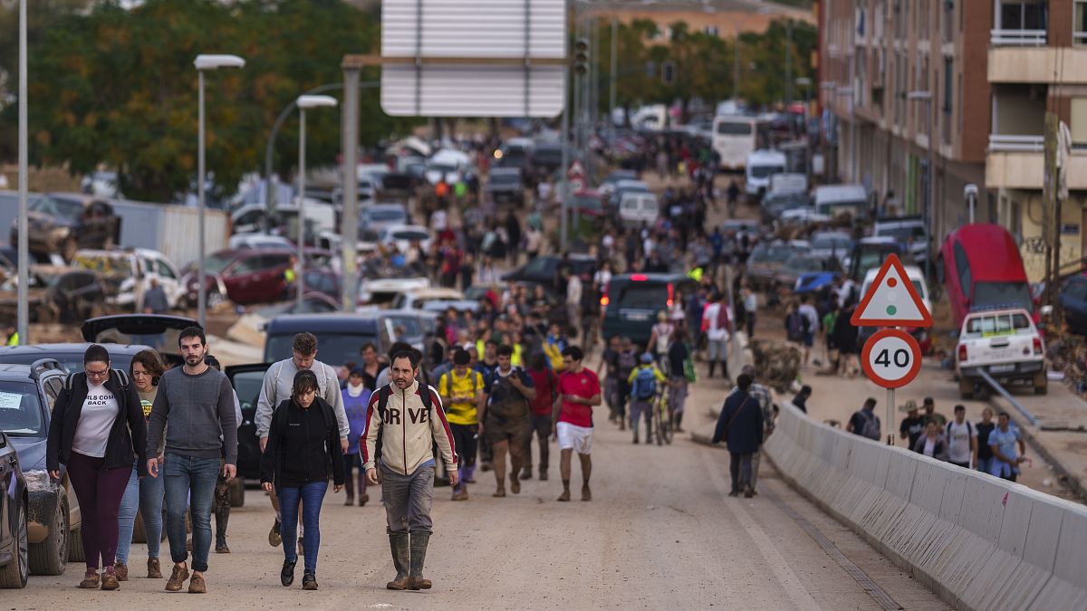 People walk toward Valencia after helping with cleaning efforts in an area affected by floods in Sedavi, 1 November, 2024