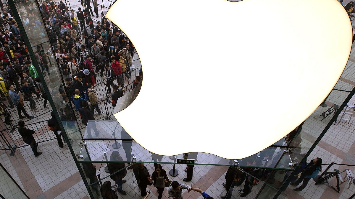 FILE - In this Saturday, Oct. 20, 2012, file photo, employees cheer customers as they enter a newly-opened Apple Store in the Wangfujing shopping district in Beijing.