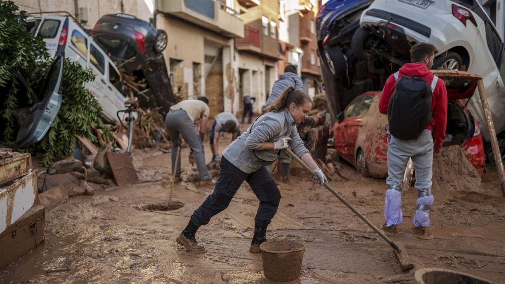 People clean the street of mud in an area affected by floods in Paiporta, 2 November, 2024