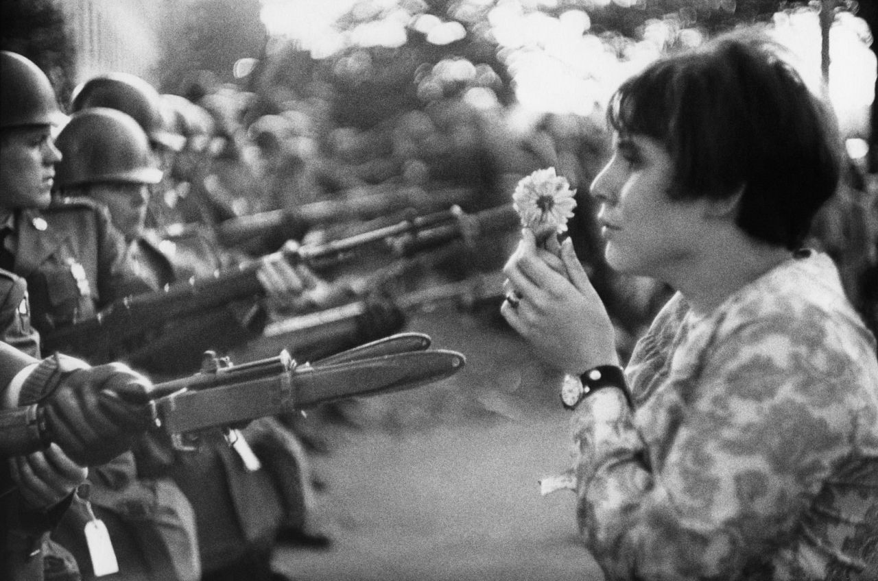 Une femme offre une fleur à un groupe de soldats.