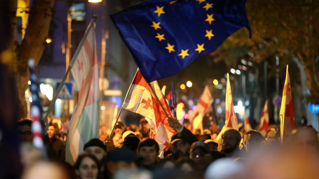 Protesters with Georgian national and an EU flags, top, take part in a rally against alleged violations in a recent parliamentary election in Tbilisi, Georgia, Nov. 4, 2024.