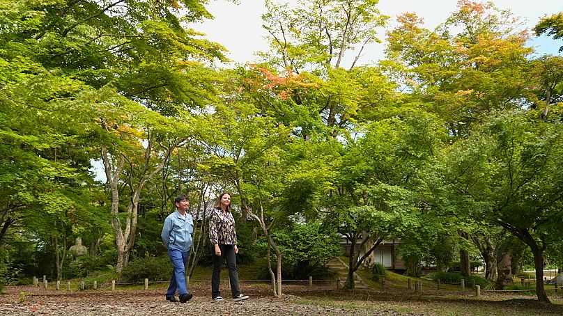 La journaliste d'Euronews Anca Ulea se promène avec le maître brasseur d'Asahi-Shuzo, Motoyoshi Yamaga, dans le jardin d'érables de Momijien