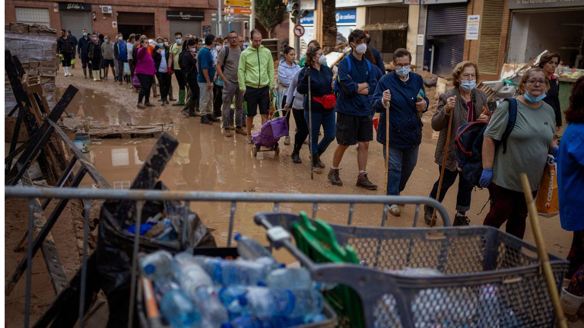 Residents wait to receive drinking water in an area, affected by floods, in Paiporta, Valencia.