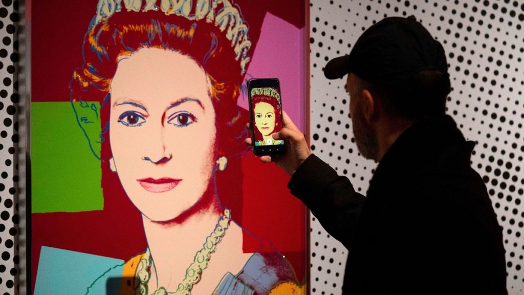 A man photographs an Andy Warhol screen print of Queen Elizabeth II, part of the 1985