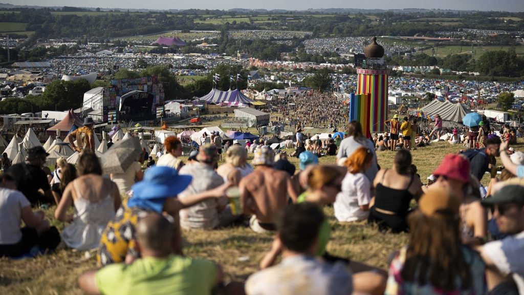 Festival goers sit on a hill at the Glastonbury Festival in Worthy Farm, Somerset, England, Wednesday, June 26, 2024