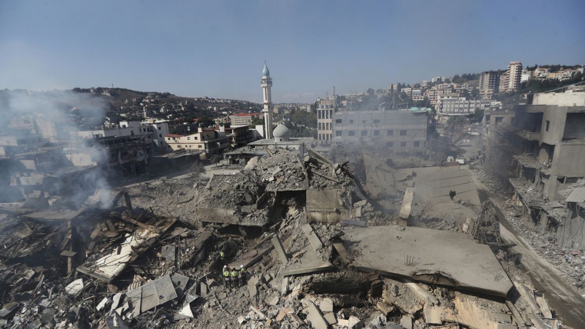 Hezbollah rescue workers, center bottom, stand on the rubble of destroyed buildings that were hit Saturday night by Israeli airstrikes, in Nabatiyeh town, south Lebanon, Sunda