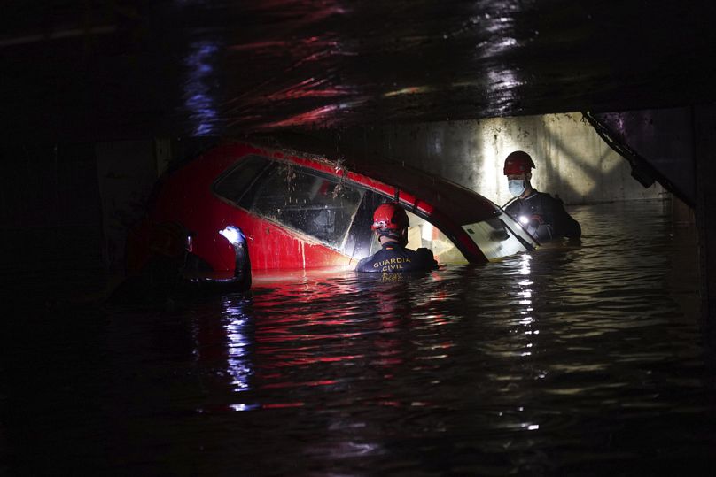 Les gardes civils vérifient les corps des voitures dans un parking couvert après les inondations à Paiporta, près de Valence, en Espagne.