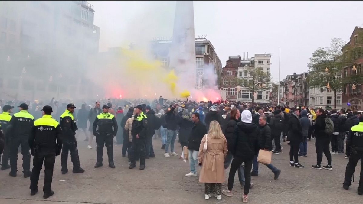 In this image taken from video, police stand guard as Maccabi Tel Aviv supporters light flares at the Dam square, in Amsterdam, the Netherlands, Thursday, Nov. 7, 2024.