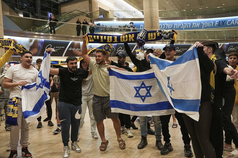 Des gens accueillent les fans de football du Maccabi Tel Aviv à leur arrivée à l'aéroport international Ben Gourion d'Israël sur un vol en provenance d'Amsterdam, le 8 novembre 2024.