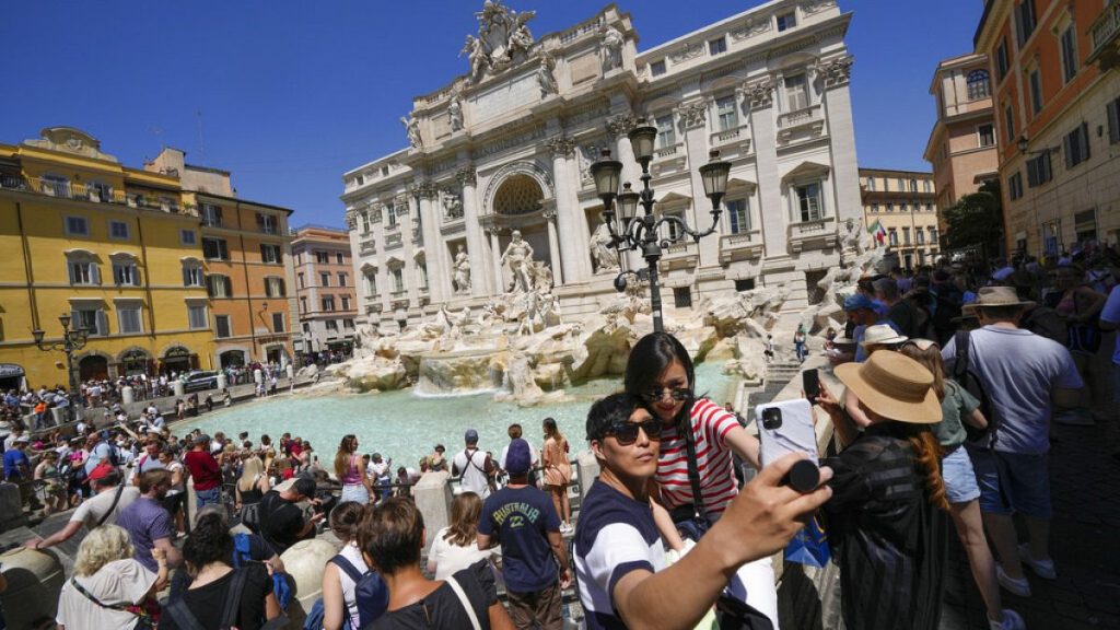 Tourists take a selfie in front of the Trevi Fountain in Rome