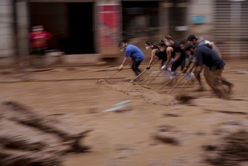 Des gens nettoient la boue d’une rue dans une zone touchée par les inondations à Catarroja, en Espagne, le lundi 4 novembre 2024. (AP Photo/Manu Fernandez)