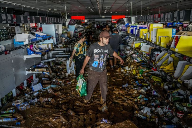 Des gens récupèrent des marchandises dans un supermarché touché par les inondations à Valence, en Espagne, le jeudi 31 octobre 2024. (AP Photo/Manu Fernandez)