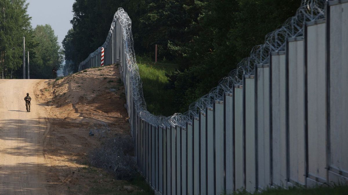 A Polish border guard patrols the area of a newly built steel wall on the border between Poland and Belarus, near Kuznice, Poland, June, 2022.