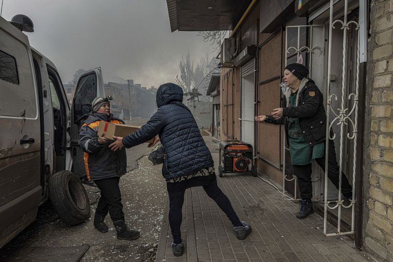 Des femmes locales déchargent des produits alimentaires d'une mini-fourgonnette dans le dernier magasin en activité à Kurakhove, dans la région de Donetsk, en Ukraine, le 7 novembre 2024. (AP Photo/Anton Shtuka)