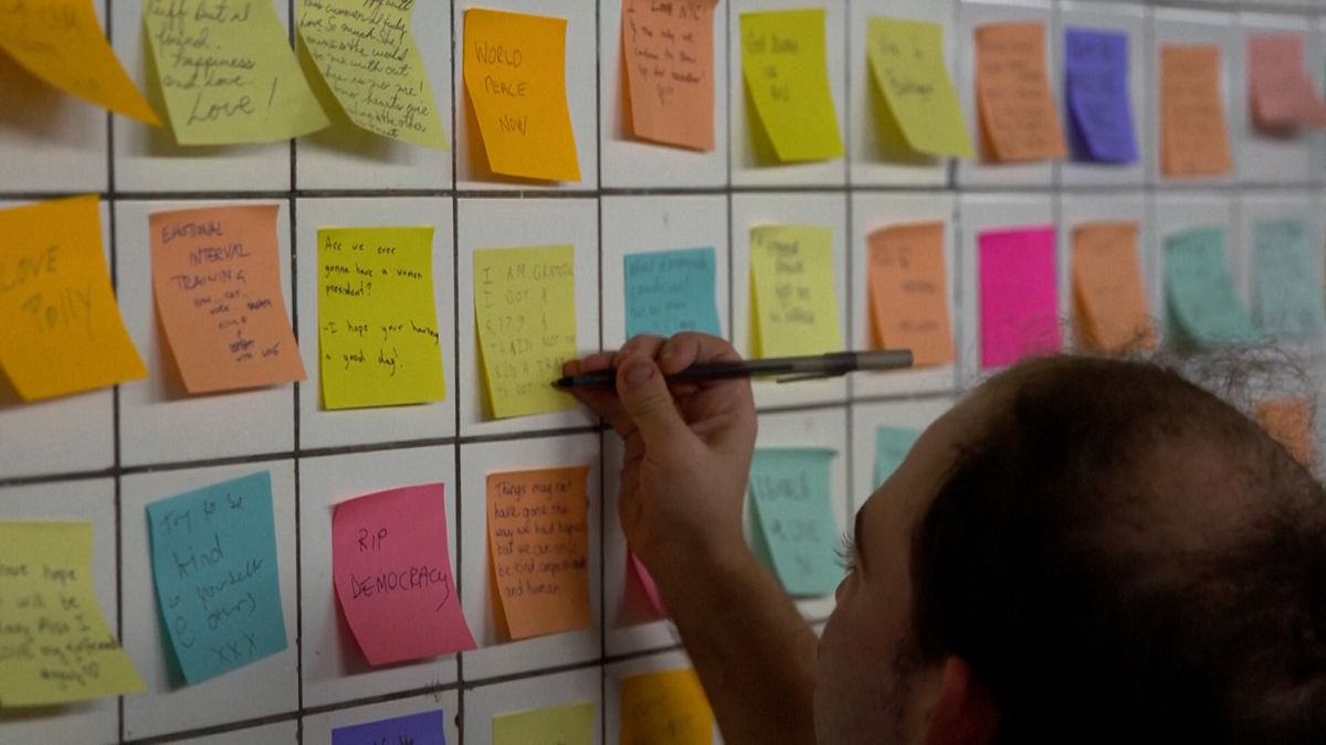 Man putting sticky note on the wall of subway tunnel as part of