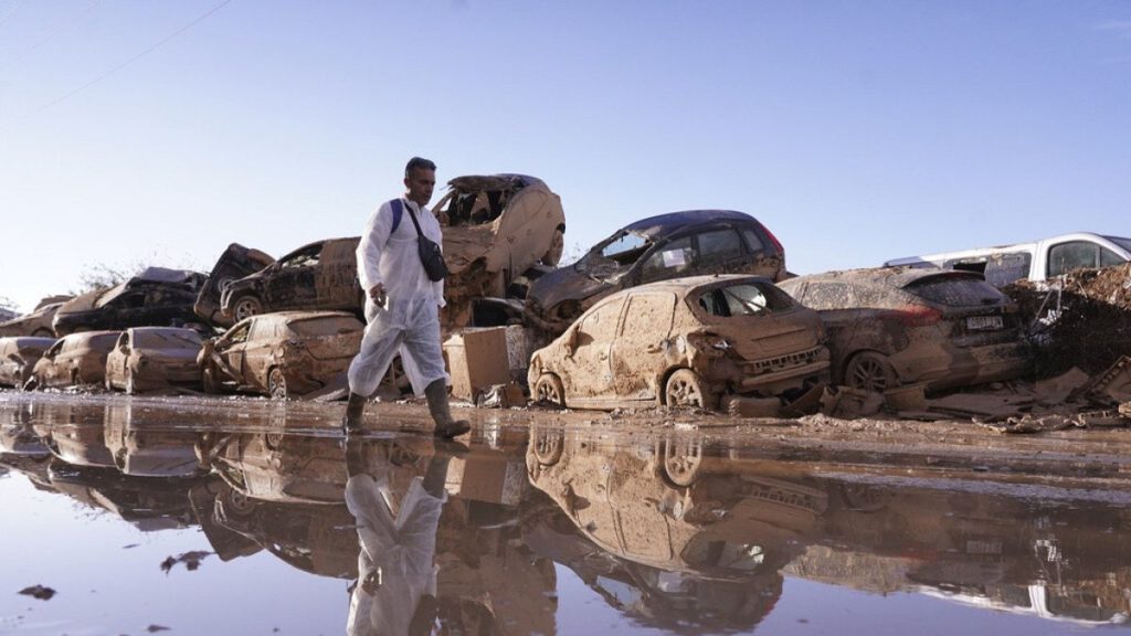 FILE: A man walks past stacked up cars after floods in Catarroja that left hundreds dead or missing in the Valencia region in Spain, Tuesday, Nov. 12, 2024.