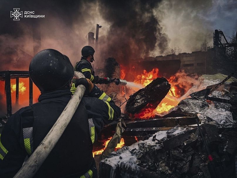 Des secouristes éteignent un bâtiment en feu détruit par une grève russe près de Kiev, le 13 novembre 2024.