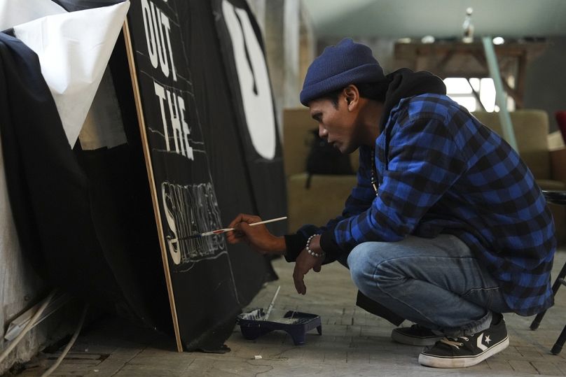 Shaq Koyok, de Malaisie, peint une pancarte avant une manifestation lors de la COP29.