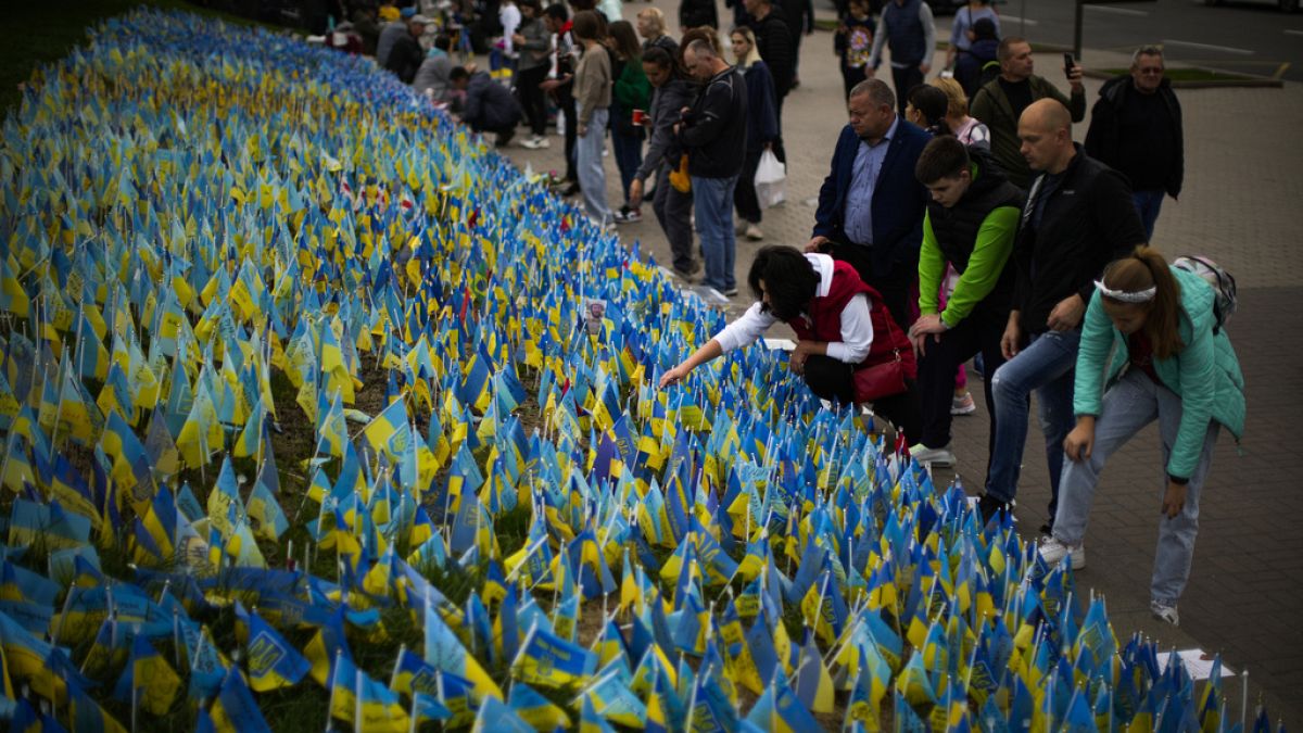 People place Ukrainian flags in memory of civilians killed during the war at Independence Square in central Kyiv, Ukraine, Saturday, Oct. 1, 2022.