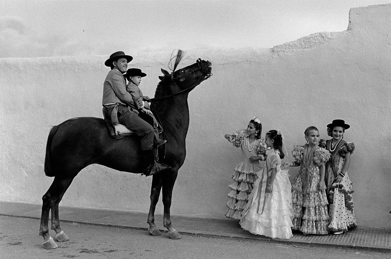 Des jeunes filles vêtues de vêtements traditionnels sévillans posent à côté d’un cheval.