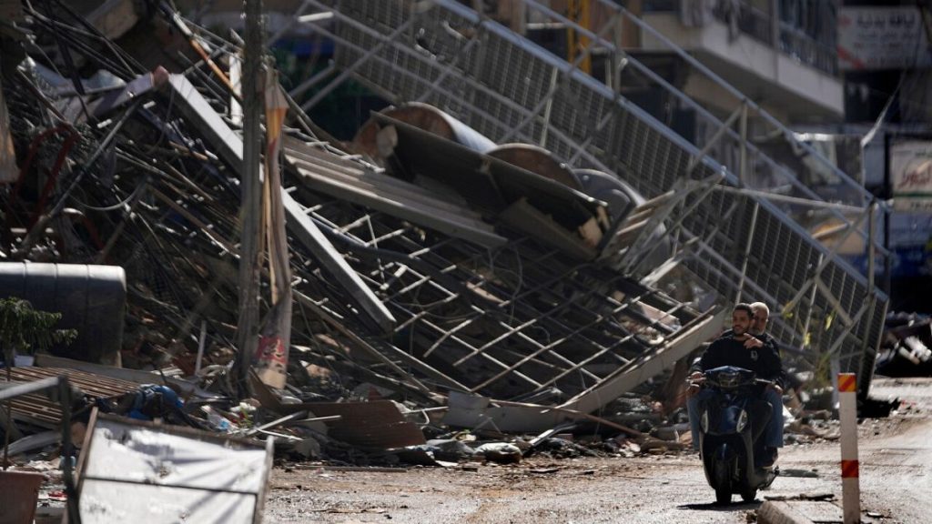 Two men ride a scooter past a building that was destroyed by an Israeli airstrike in Dahiyeh, in the southern suburb of Beirut, Lebanon, Monday, Nov. 11, 2024.