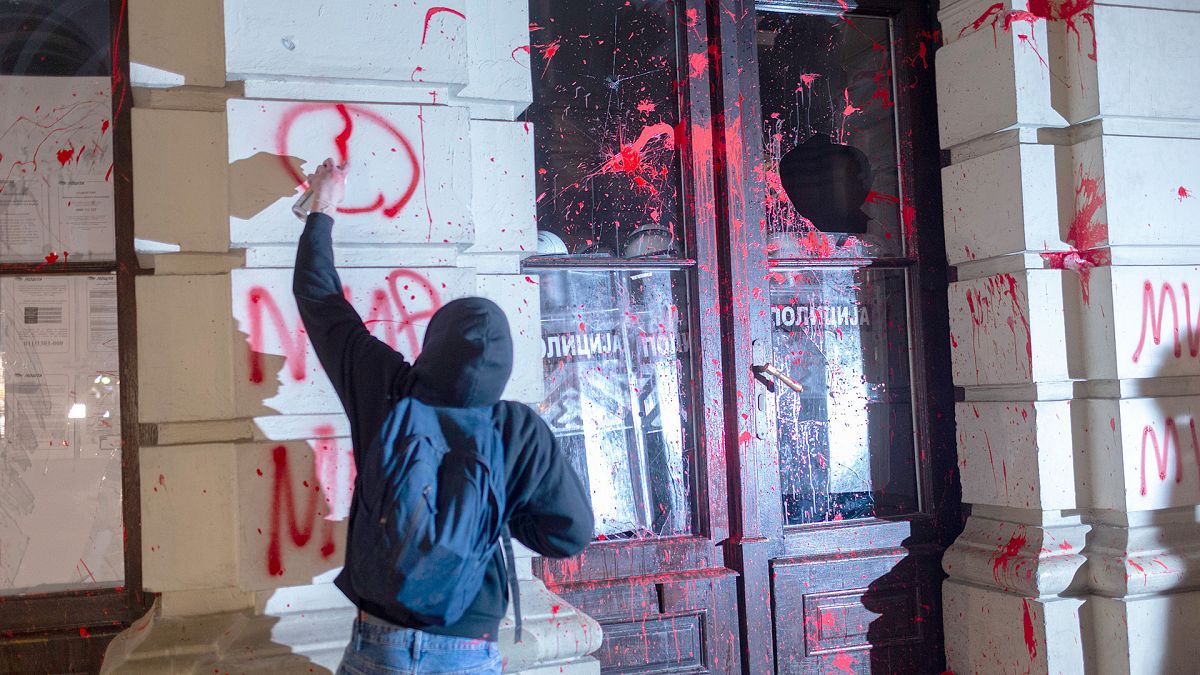 A protester paints grafitti on the City Hall during a protest in rage over last week