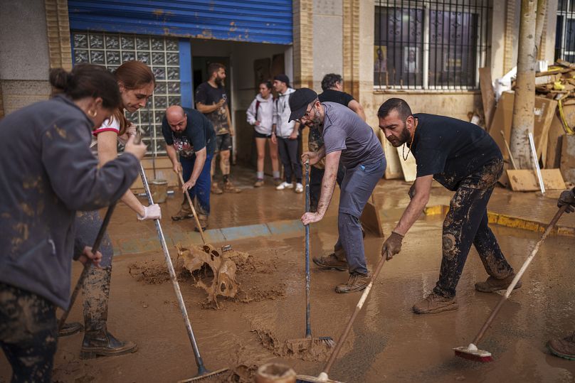 Des gens nettoient la rue de la boue dans une zone touchée par les inondations à Sedavi, le 1er novembre 2024