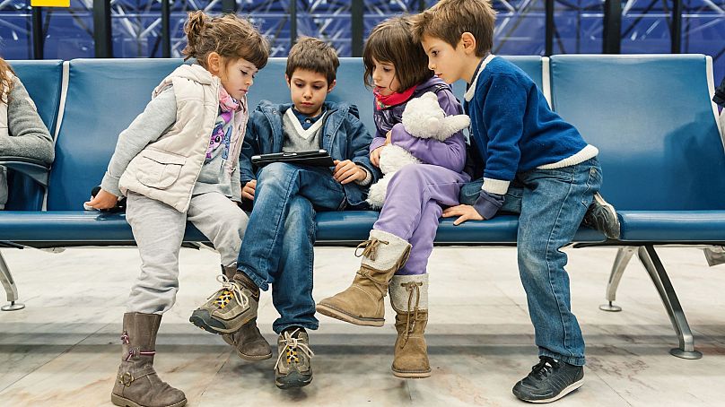 Les enfants attendent un vol à l’intérieur de l’aéroport de Lisbonne la nuit