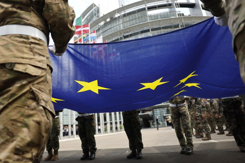 Des militaires brandissent le drapeau de l'Union européenne alors qu'ils participent à une cérémonie de lever du drapeau devant le Parlement européen à Strasbourg, en juillet 2024.