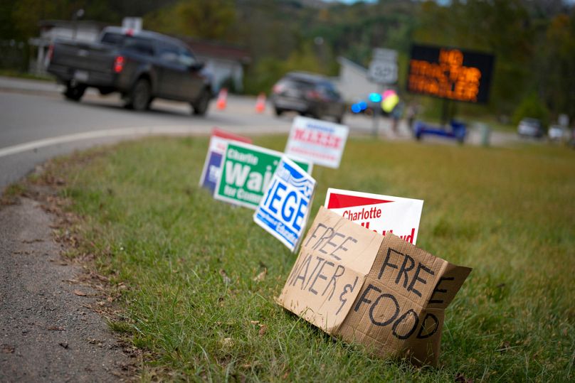 Un panneau de fortune en carton s'appuie contre des affiches de campagne près d'un centre de secours le jeudi 3 octobre 2024 à Vilas, Caroline du Nord.